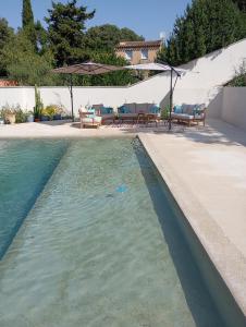 a pool of water with chairs and an umbrella at Studio avec piscine in Nîmes
