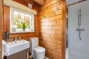 a bathroom with a toilet and a sink and a window at Lake View Lodge with Hot Tub in Thirsk +36 photos