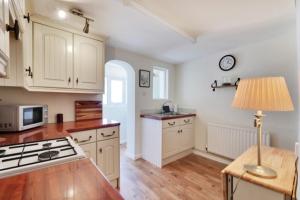 eine Küche mit weißen Schränken und einem Tisch mit einer Lampe in der Unterkunft Fisherman's Cottage in Hastings Old Town in Hastings