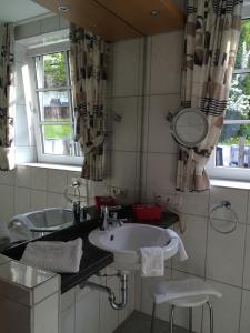 a bathroom with two sinks and a mirror at Landhotel Menke in Brilon