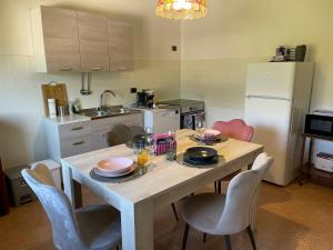 a kitchen with a wooden table with chairs and a refrigerator at Villa Debora in Ponte nellʼAlpi