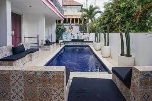 a swimming pool with couches and cactus in a backyard at Margarita Surf Hostel Canggu in Canggu