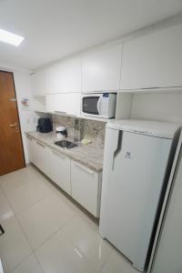 a white kitchen with a sink and a microwave at Gold flat praia de cabo branco in João Pessoa
