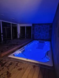 a large jacuzzi tub in a room with blue lighting at Escapade Romantique à Saint Omer-Espace Totalement Privatisé Avec Terrasse in Saint-Omer