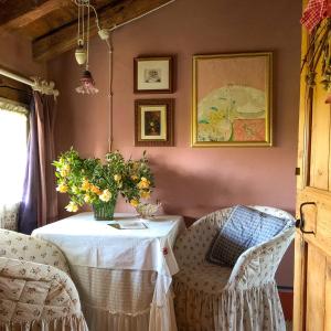 a table with a vase of flowers and a chair at Maso Di Villa Relais di Campagna in Susegana