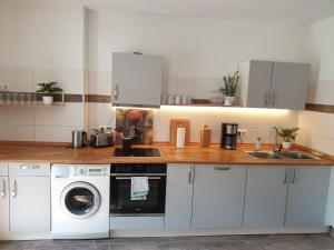 a kitchen with white cabinets and a washer and dryer at Altes Forsthaus Laubusch in Lauta