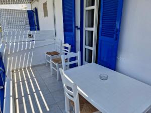 a table and chairs on a balcony with a blue door at Katerina Yalos in Ios Chora +32 photos