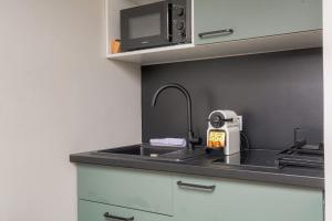 a kitchen counter with a sink and a microwave at Studio cosy, climatisé, Caluire-Lyon in Caluire-et-Cuire