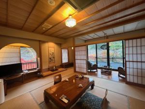 a living room with a table and chairs and windows at すいこうえんさくら in Fujinomiya