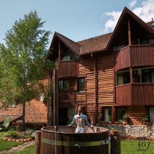 Una niña parada en un barril frente a una casa. en Art'e Boutique Rooms, en Băile Tuşnad