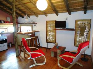 sala de estar con sillas rojas y cocina en Arándanos, en Punta del Diablo