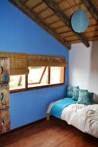 Cama en habitación con pared azul en Arándanos, en Punta del Diablo