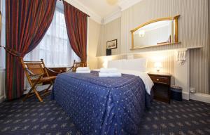 Habitación de hotel con cama y espejo en Regency House Hotel, en Londres