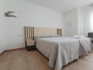 a white bedroom with a bed and a chair at El Hostalito in Fuensanta