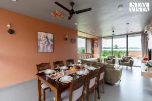 a dining room with a table and a couch at StayVista at Terracotta Skies with Courtyard & Pool in Nashik