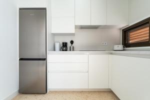 a kitchen with white cabinets and a refrigerator at CT 288 AL - Faro's Retamar Cuddly Nest for 2 in Almería