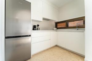 a kitchen with white cabinets and a stainless steel refrigerator at CT 288 AL - Faro's Retamar Cuddly Nest for 2 in Almería +12 photos