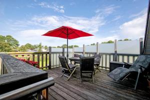 patio con tavolo, sedie e ombrellone rosso di Ferienwohnung Windrose a Waldhusen