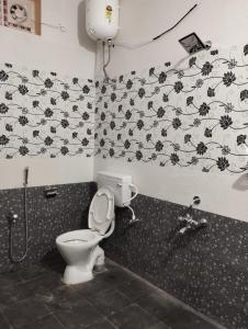 Un baño con inodoro y papel pintado en blanco y negro. en Villa Eden 1bhk, en Pondicherry