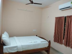 Un dormitorio con una cama con ventilador de techo. en Villa Eden 1bhk, en Pondicherry