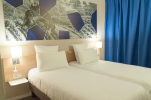 a bedroom with a white bed with a blue curtain at Brit Hotel M&acirc;con Centre Gare in M&acirc;con