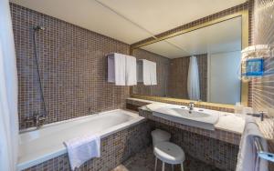 a bathroom with a tub and a sink and a mirror at Hotel Marhaba Beach in Sousse
