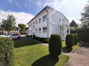 une maison blanche avec une voiture garée devant elle dans l'établissement Villa Herbstwind in Binz, à Binz