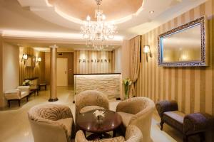 a lobby with chairs and a table and a chandelier at Garni Hotel President de Luxe in Kragujevac