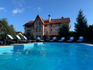 a swimming pool with chairs and a building in the background at Villa Alessia in Skhidnitsa