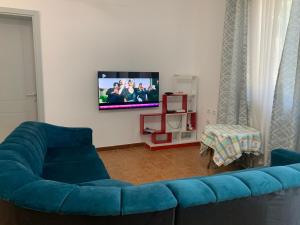 a living room with a blue couch and a tv at Velipoja Sea House in Velipojë