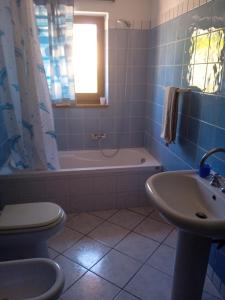 a bathroom with a tub and a toilet and a sink at Appartamento Pisturri in Magomadas
