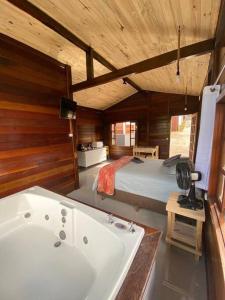 a bathroom with a bath tub and a bed at Encanto da Mata - Chalé Ipê - Lavras Novas-MG in Lavras Novas +5 photos