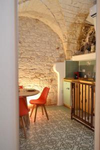 a kitchen with a table and chairs and a stone wall at Casa Philos in Ceglie Messapica