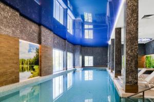 a large swimming pool with a blue ceiling at Hotel Półwysep Wądzyn in Bobrowo