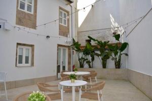 a patio with two tables and chairs and plants at Corona de Galicia Rooms in Padrón