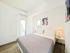 a white bedroom with a bed and a window at Marathonomachon by Verde Apartments in Athens