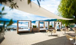 a patio with chairs and tables and a white canopy at Lake's in Pörtschach am Wörthersee