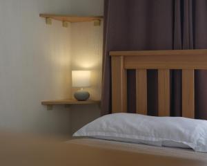a bed with a wooden headboard and a table with a lamp at 1870 Hotel in Kutaisi