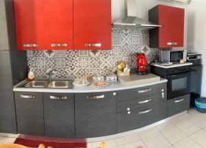 a kitchen with black cabinets and red cupboards at B&B Mura 17 in Polistena