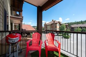 two red chairs and a grill on a balcony at Trailhead Lodges 821 in Winter Park