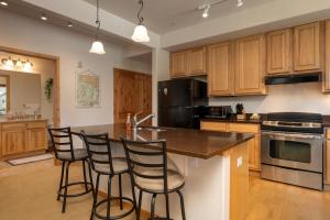 a kitchen with wooden cabinets and a island with bar stools at Trailhead Lodges 821 in Winter Park +14 photos