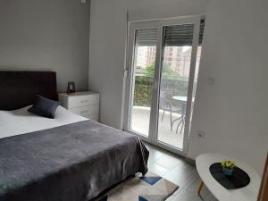 a bedroom with a bed and a balcony with a table at BOKI apartments in Bijela