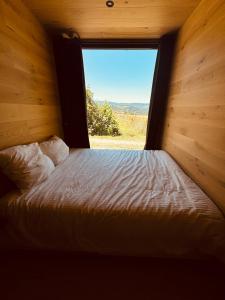 un letto in una camera con una grande finestra di La Cabane de Pierrot a Saint-Bonnet-le-Courreau Altre 30 foto