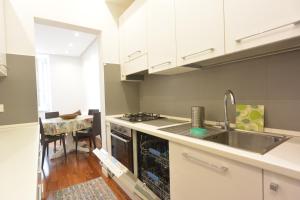 a kitchen with white cabinets and a sink and a table at Felix House in Savona