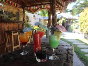 a table with four different colored drinks on it at eco trekking lodge, Co Bar & jungle tour's only booking with us ! in Bukit Lawang