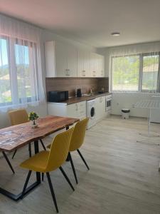 a kitchen with a wooden table and yellow chairs at Апартаменти за гости Сузи in Zavoya +13 photos