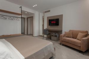 a bedroom with a bed and a chair and a tv at Alexander House Hotel in San Ferdinando