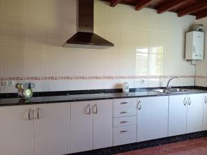 a kitchen with white cabinets and a sink at Casa independiente Solana in O Lourido +9 photos