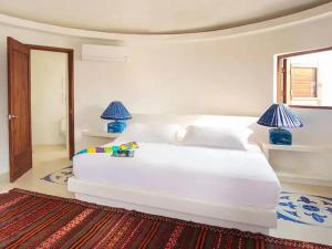 une chambre avec un grand lit blanc avec deux lampes dans l'établissement Isla Pelícano, à Isla Grande