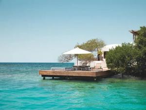 - un quai avec des chaises et un parasol sur l'eau dans l'établissement Isla Pelícano, à Isla Grande